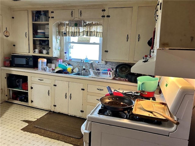 kitchen featuring cream cabinetry, white range, tasteful backsplash, and sink