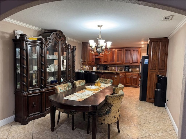 dining space featuring a textured ceiling, crown molding, and a chandelier