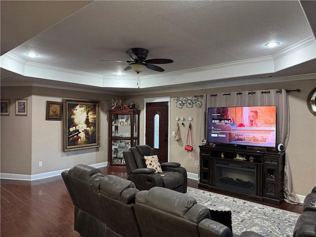 living room with ornamental molding, a textured ceiling, a tray ceiling, ceiling fan, and dark hardwood / wood-style floors