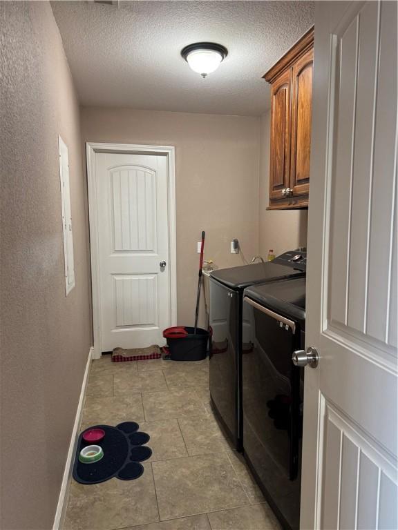 laundry room featuring cabinets, a textured ceiling, and independent washer and dryer