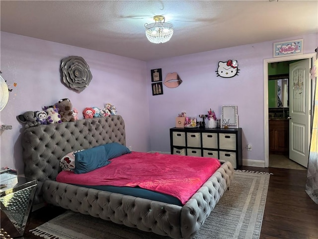 bedroom featuring dark hardwood / wood-style floors, ensuite bathroom, and an inviting chandelier