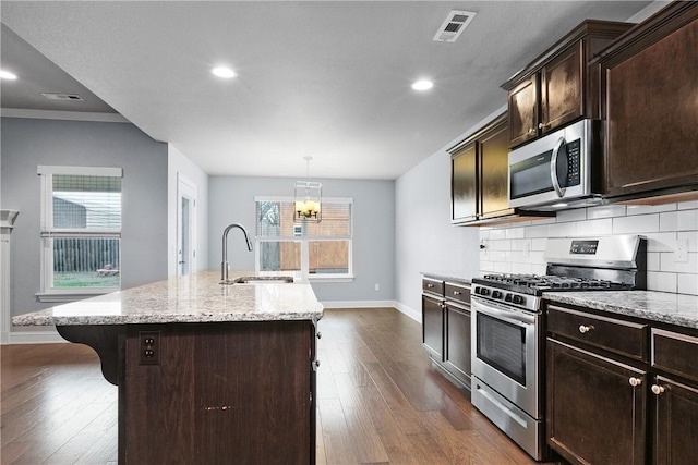 kitchen featuring sink, a breakfast bar area, appliances with stainless steel finishes, a kitchen island with sink, and backsplash