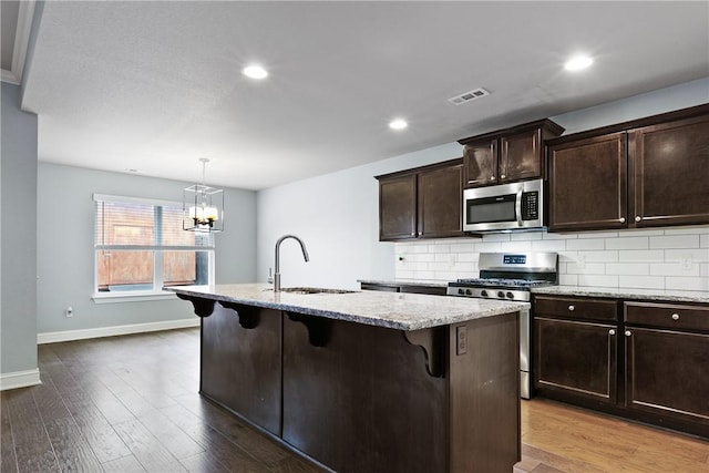 kitchen with sink, tasteful backsplash, a center island with sink, a kitchen breakfast bar, and stainless steel appliances