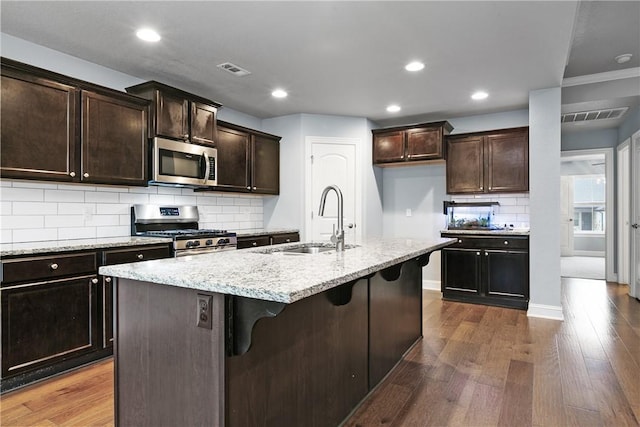 kitchen featuring appliances with stainless steel finishes, dark hardwood / wood-style flooring, sink, and a center island with sink