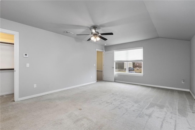 interior space with ceiling fan, a walk in closet, lofted ceiling, and light carpet