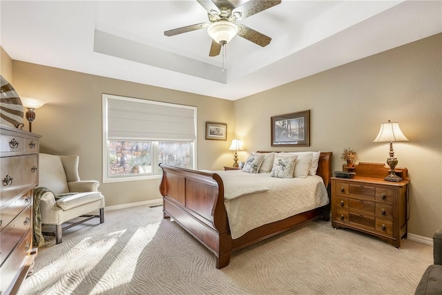 carpeted bedroom featuring ceiling fan and a tray ceiling