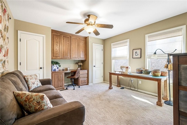 office with built in desk, ceiling fan, and light carpet