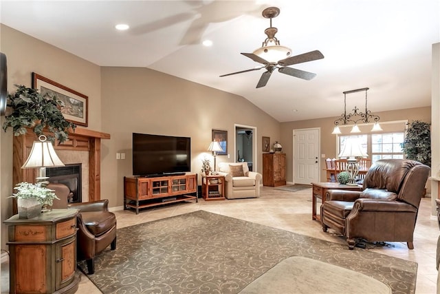 tiled living room with a tile fireplace, ceiling fan, and vaulted ceiling