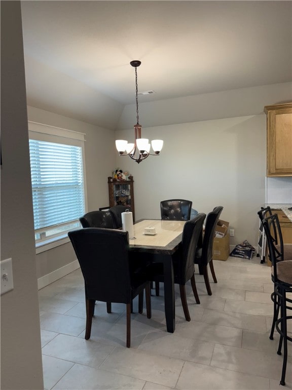 tiled dining space with an inviting chandelier and lofted ceiling