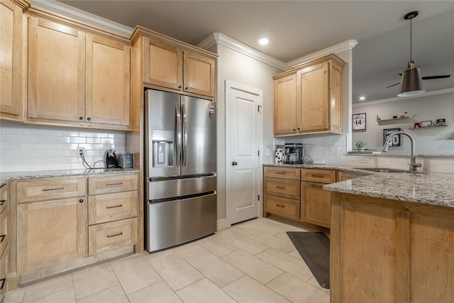 kitchen featuring light stone countertops, stainless steel fridge, backsplash, and sink