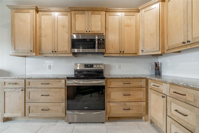 kitchen featuring appliances with stainless steel finishes, light tile patterned floors, light brown cabinetry, and light stone counters