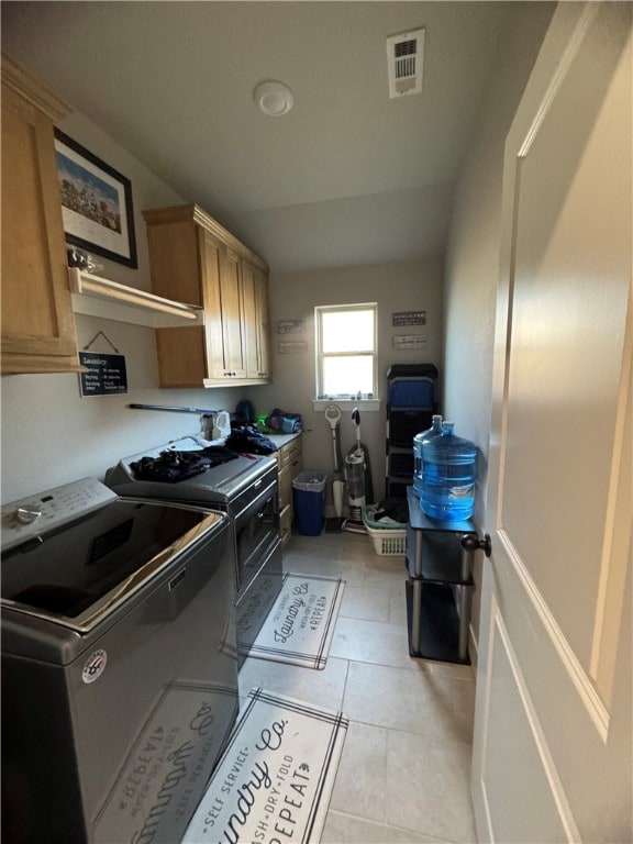 laundry area featuring cabinets, separate washer and dryer, and light tile patterned flooring