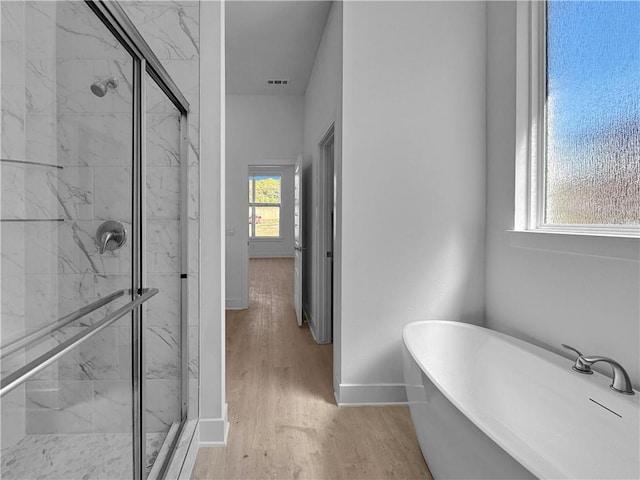 bathroom with hardwood / wood-style floors, separate shower and tub, and a healthy amount of sunlight