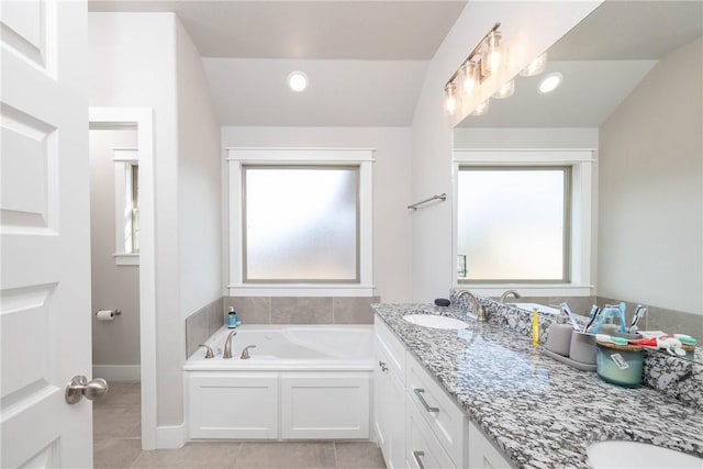 bathroom with a wealth of natural light, tile patterned flooring, vanity, and a bath