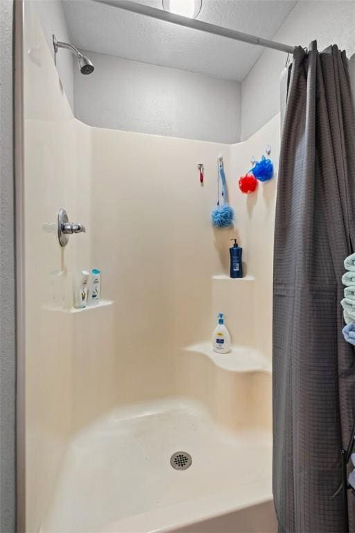 bathroom featuring curtained shower and a textured ceiling