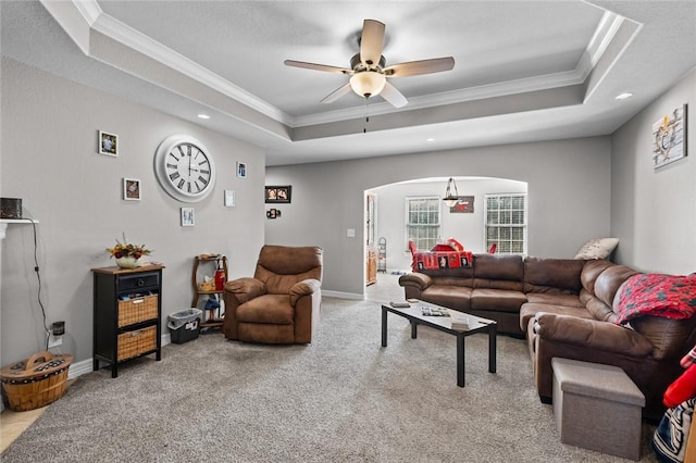 living room featuring light carpet, a raised ceiling, ceiling fan, and crown molding