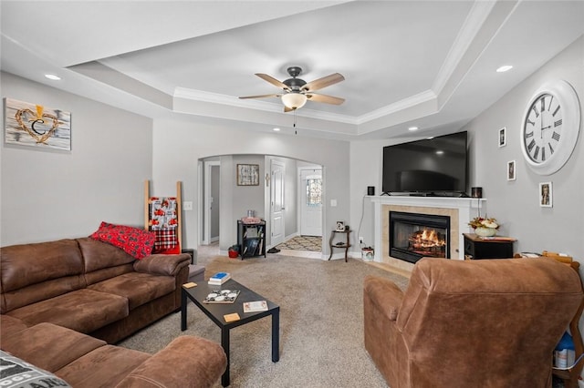 carpeted living room featuring a tray ceiling, ceiling fan, and ornamental molding