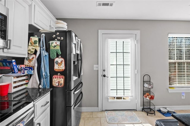 kitchen with a healthy amount of sunlight, white cabinetry, and dark stone counters