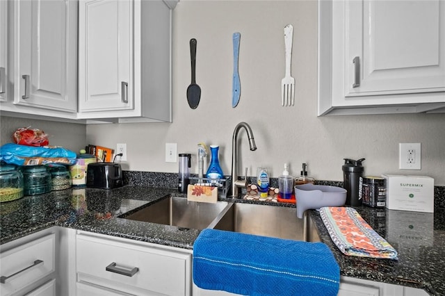 kitchen with dark stone countertops and white cabinetry