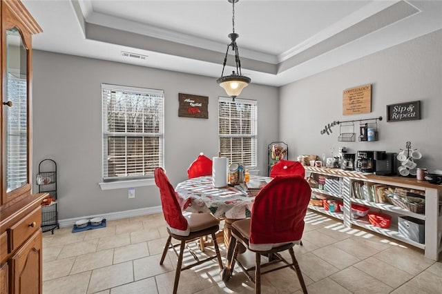 tiled dining room featuring a raised ceiling and ornamental molding