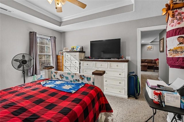 carpeted bedroom featuring a tray ceiling, ceiling fan, and crown molding