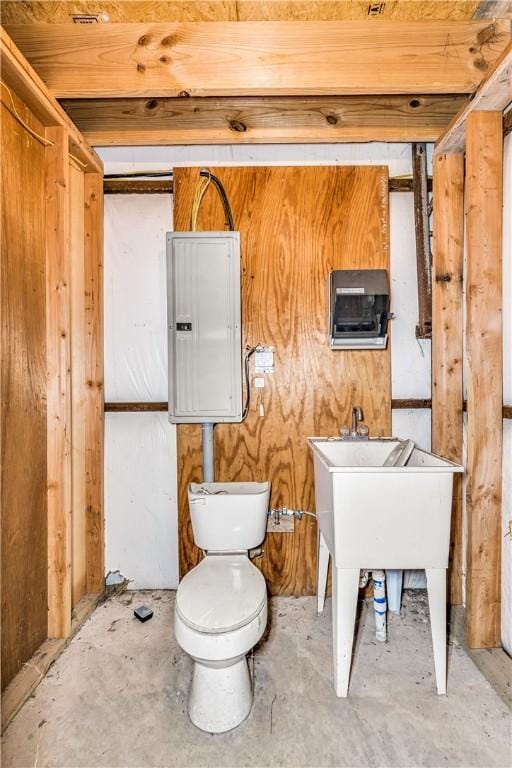 bathroom featuring toilet, electric panel, and concrete floors