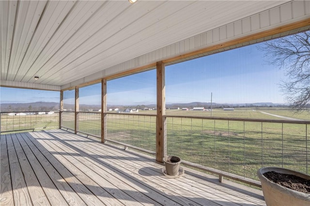 wooden terrace featuring a rural view and a lawn