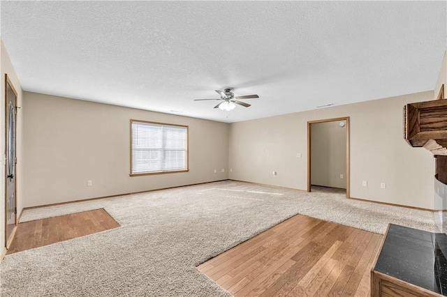 unfurnished living room featuring ceiling fan, light carpet, and a textured ceiling