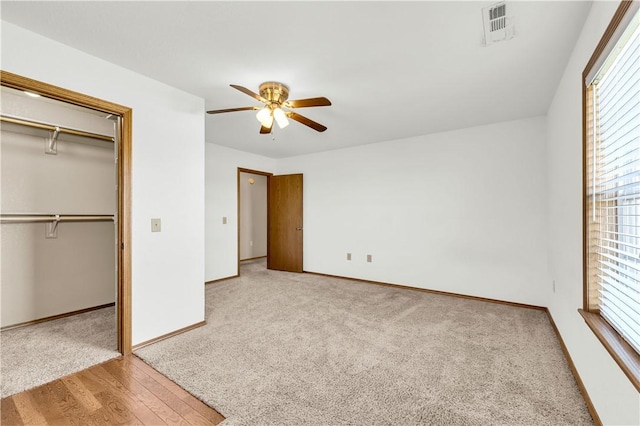 unfurnished bedroom with ceiling fan, a closet, carpet floors, and multiple windows