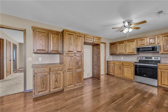 kitchen featuring ceiling fan, appliances with stainless steel finishes, and dark hardwood / wood-style flooring