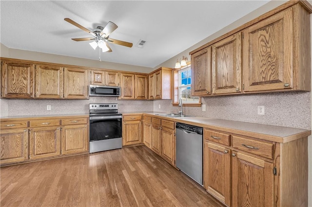 kitchen featuring ceiling fan, appliances with stainless steel finishes, sink, and light hardwood / wood-style flooring