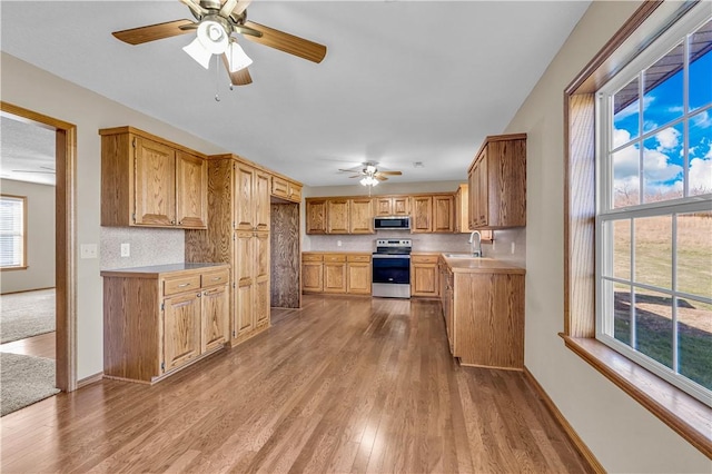 kitchen with stainless steel appliances, wood finished floors, a sink, and light countertops