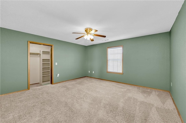 unfurnished bedroom with ceiling fan, light colored carpet, a closet, and a walk in closet