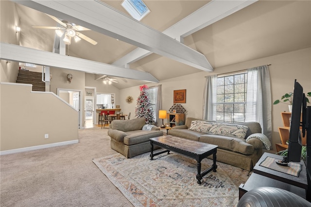 carpeted living room with ceiling fan and vaulted ceiling with skylight