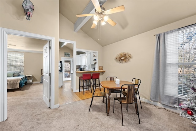 carpeted dining area with ceiling fan and vaulted ceiling