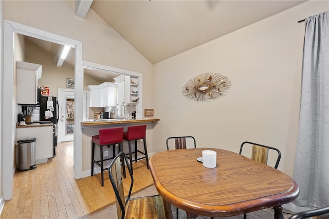 dining room with sink, lofted ceiling, and light wood-type flooring