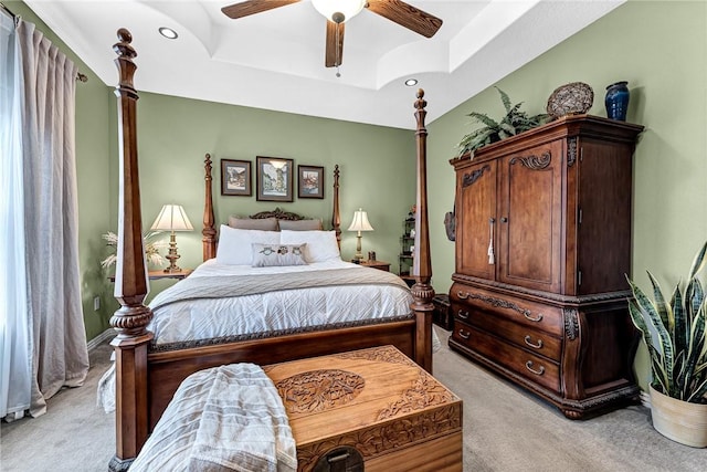 bedroom featuring a ceiling fan, a raised ceiling, and light carpet