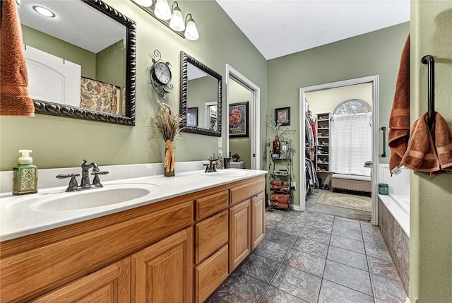 bathroom featuring a spacious closet, double vanity, and a sink