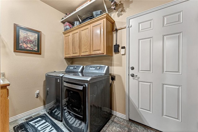 washroom with cabinet space, baseboards, and independent washer and dryer