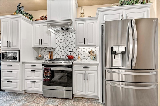 kitchen with white cabinets, light stone counters, stainless steel appliances, premium range hood, and backsplash