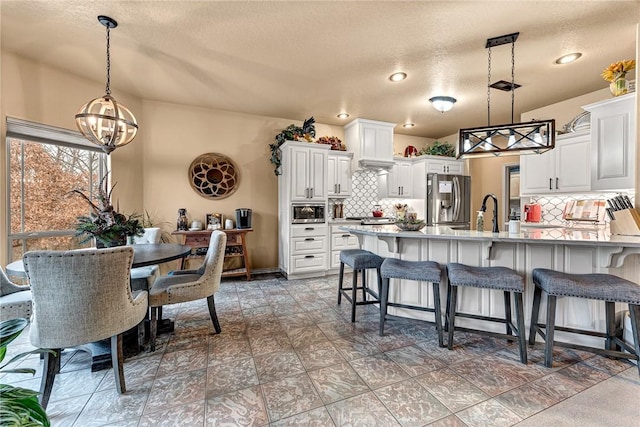 kitchen featuring stainless steel appliances, a peninsula, a sink, white cabinetry, and a kitchen breakfast bar