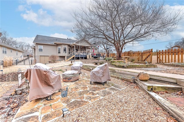 back of house with a deck, a patio, a fenced backyard, a fire pit, and stairway