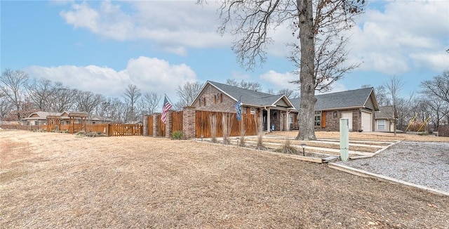 view of front of house with an attached garage, fence, and brick siding