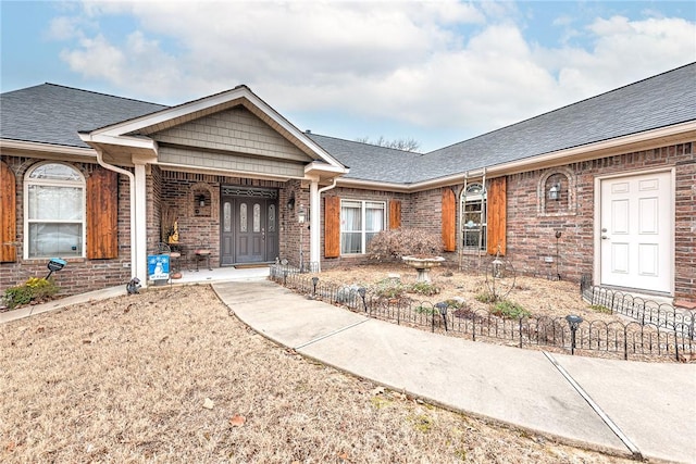 view of front of house with a shingled roof and brick siding