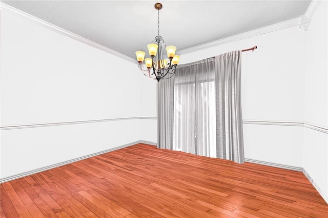 spare room featuring a textured ceiling, ornamental molding, wood finished floors, and a notable chandelier