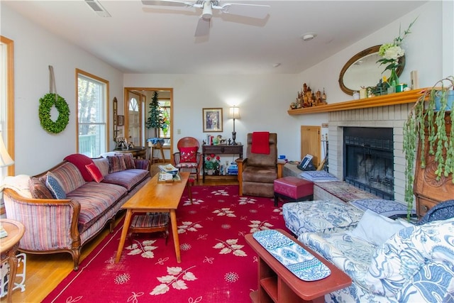 living room with ceiling fan, hardwood / wood-style floors, and a brick fireplace