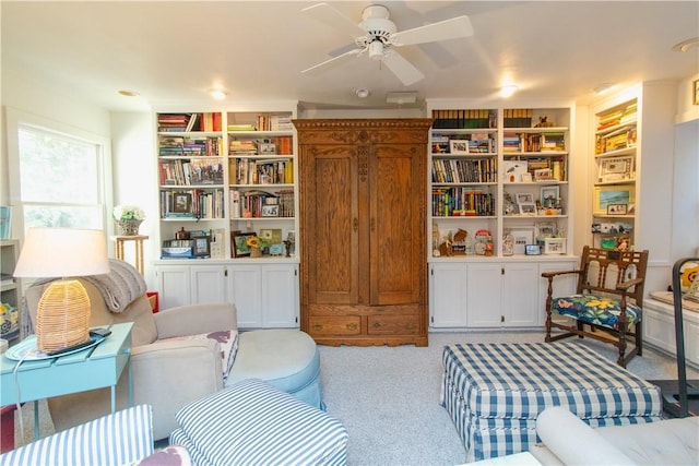 living area with light carpet, built in features, and ceiling fan