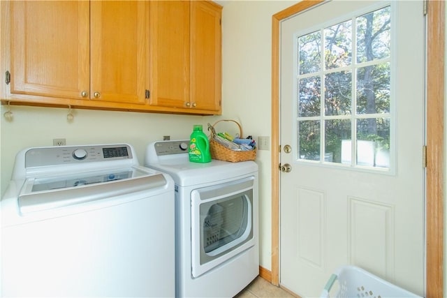 clothes washing area with cabinets, light tile patterned floors, and washer and clothes dryer