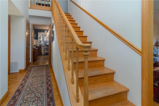 stairs featuring hardwood / wood-style floors and a high ceiling