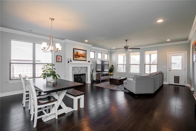 dining area with ceiling fan with notable chandelier, a tile fireplace, crown molding, and dark hardwood / wood-style flooring